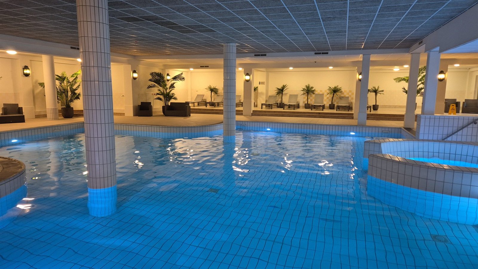 Het binnenbad van Hotel Heerlickheijd van Ermelo met warme verlichting en palmen